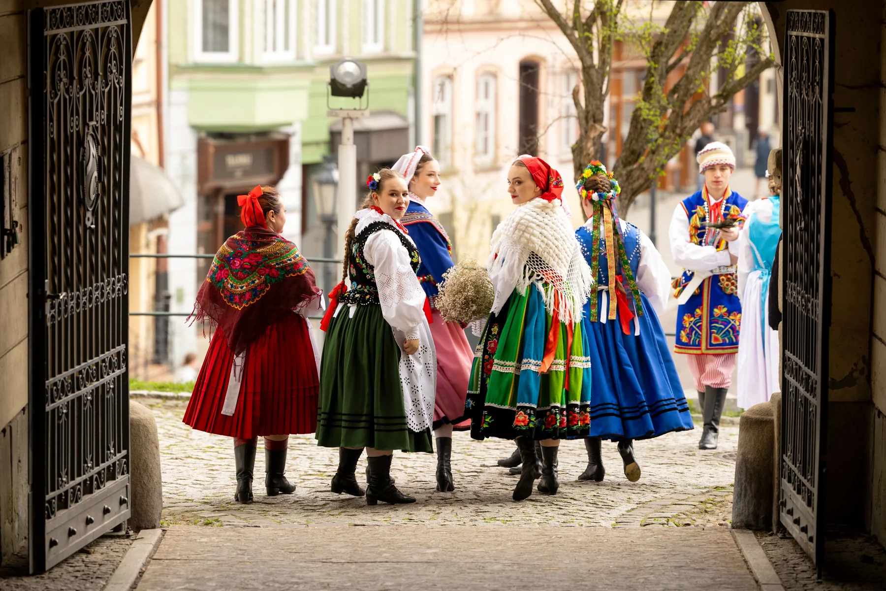 Grupa tancerzy w strojach ludowych w bramie